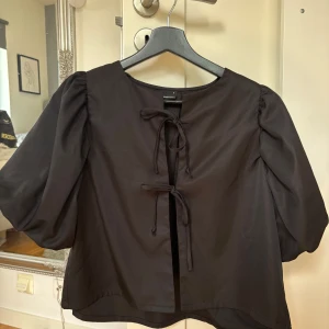 Svart topp - Svart topp med knytning framtill från Gina i storlek S. Fint skick!