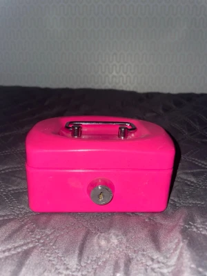 Ett fint kassaskåp  - En liten rosa metallbox med handtag och lås. Inte så neon rosa som det är på bilden så ni vet🤭 