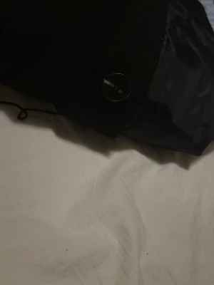 Svart kofta med knappdetalj - Säljer en svart kofta med klassisk knappstängning. Koftan har en mjuk och slät yta med insida i blankt tyg, vilket ger en stilren look. Perfekt för dig som gillar enkla och tidlösa plagg.