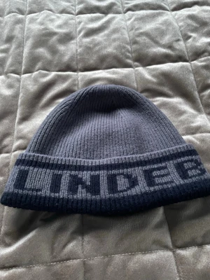 J Lindeberg mössa - Säljer en grå stickad mössa från J.Lindeberg. Knappt använd så den är i väldigt gott skick. Skriv gärna för mer info.