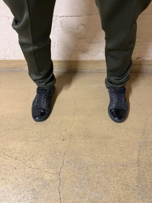 Svarta sneakers från Lanvin i mocka - Säljer ett par svarta sneakers från Lanvin med snygg kontrast mellan mocka och glansig tå i skinn. Skorna har rund tå, snörning och platt sula. Perfekta för dig som gillar stilrena och klassiska sneakers med en twist.