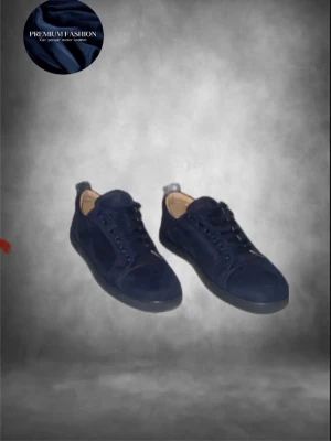 Mörkblå mocka sneakers Christian Louboutin - Snygga mörkblå sneakers från Christian Louboutin i mjuk mocka med klassisk röd signatursula. Storlek 41 sitter som 41,5 / 42. Skorna är i dunder skick förutom en liten skavank, som ni ser på bild 3 är ringen borta men inget som märks eller syns på avstånd! Skorna kommer med tags och allt annat även box! Hör av dig vid minsta fundering 🤩