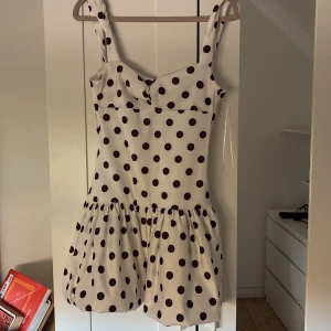 Vit kort klänning med svarta prickar - Svart prickig klänning från zara i minsta storleken, tror det är S men passar mig som har xs/S perfekt.  Skriv vid eintresse av fler bilder. Har bara använts två gånger och är i jättefint skick