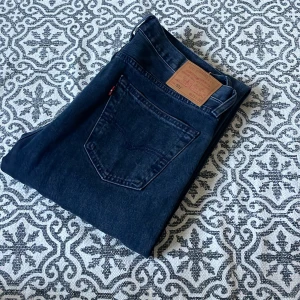 Levi's 501 jeans blå & svarta W33 L32 - Två par klassiska Levi's 501 jeans, ett par i mörkblå denim och ett par i svart. Båda har raka ben, femficksdesign och ikonisk läderpatch bak. Perfekta för dig som gillar tidlös stil och vill ha ett par jeans som alltid funkar.