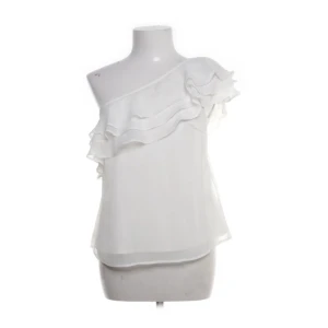 Vit oneshoulder topp från Bubbleroom - Säljer en vit oneshoulder topp från Bubbleroom by Carolina Gynning i storlek 34. Toppen har volangdetaljer längs axeln och är tillverkad i ett lätt, luftigt tyg som ger en snygg och feminin look. Perfekt för dig som gillar stilrena och trendiga plagg.