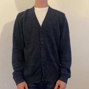 Mörkblå Pier Ole kofta - Snygg mörkblå kofta från Pier One med v-ringning och fyra knappar framtill. Koftan är stickad i mjukt material och har långa ärmar samt ribbade muddar. Modellen är 180 cm lång.