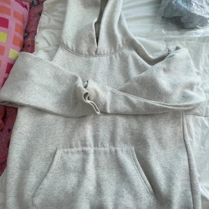 Ljusgrå hoodie från Essentials - Säljer en stilren ljusgrå hoodie från Essentials Fear of God. Hoodien har en klassisk känguruficka, huva och ribbade muddar. Perfekt för dig som gillar en clean och enkel look. Passar till allt och är supermjuk på insidan.