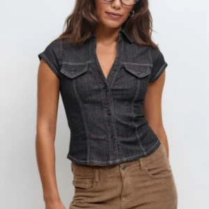  jeansskjorta från Gina tricot  - Säljer en  jeansskjorta från Gina tricot  med korta ärmar, markerad midja och coola bröstfickor med knappar. Skjortan har klassisk krage och synliga sömmar som ger en snygg retrovibe. Aldrig använd och prislappar finns på 