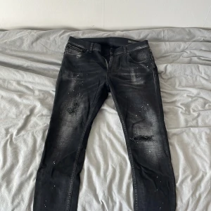 Svarta Dondup jeans med slitningar, stl 30 - Svarta jeans från Dondup i storlek 30 med coola slitningar och färgstänk på benen. Modellen har en smal passform och klassisk femficksdesign. Jeansen har en snygg tvättad look och är tillverkade i jeansmaterial med stretch för extra komfort. Skriv gärna om du har frågor😁