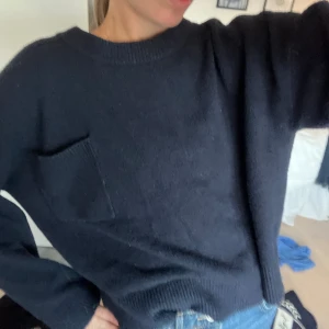 Mörkblå stickad tröja från Zara - Säljer en mörkblå stickad tröja från Zara med rund hals och en snygg bröstficka. Tröjan har lång ärm och en loose passform som ger en chill vibe. Perfekt att matcha med jeans eller kjol för en enkel och stilren look.