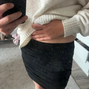 Svart tight kortkjol - Säljer en svart tight kortkjol med snygga draperade detaljer. Kjolen har en kroppsnära passform och är perfekt för dig som gillar en stilren och enkel look. Passar dig som vill ha en klassisk svart kjol med lite extra edge.