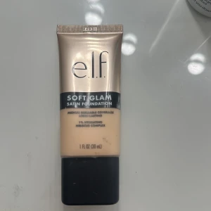 e.l.f. Soft Glam Satin Foundation - Foundation från e.l.f. i nyansen Soft Glam med satin-finish. Ger medium täckning och har en återfuktande formula med hibiskuskomplex. Tuben är beige med svart lock och rymmer 30 ml. Testas på haden endast av mig. Där av är den inte använd som ohygienisk