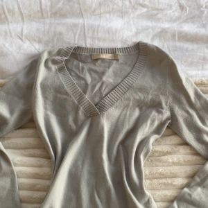 Ljusgrå v-ringad tröja från G2000 - Snygg ljusgrå v-ringad tröja från G2000 med ribbade kanter vid halsringningen. Tröjan har lång ärm och är tillverkad i ett mjukt, stickat material som känns jätteskönt. Perfekt nu för hösten!🍁💕 Är i storlek ”5” vilket jag skulle säga är xs-s.