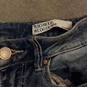 Bootcut jeans från Vero Moda - Köpare står för frakt! Snygga ljusblå bootcut jeans från Vero Moda med klassisk femficksdesign och slitningar på ena benet. Jeansen har hög midja och är tillverkade i mjukt denimtyg med lätt stretch för skön passform. Perfekt för dig som gillar retrovibbar och avslappnad stil.
