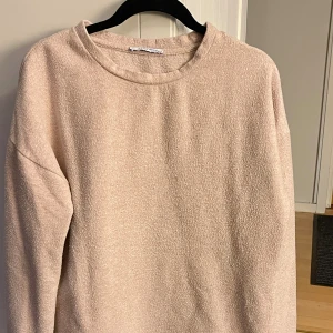 Rosa mysig långärmad tröja - Supermjuk och enkel ljusrosa/smutstosa tröja med lång ärm och rund hals. Tröjan har en avslappnad passform och är gjord i ett fluffigt, stickat material som känns riktigt skönt mot huden. Perfekt för kyliga dagar när du vill vara både bekväm och snygg.