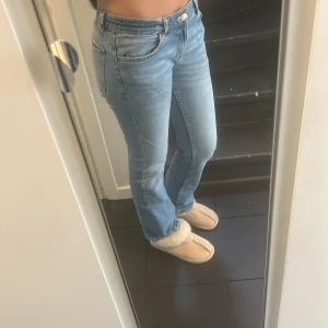 Ljusblå bootcut jeans - Säljer ett par ljusblå jeans med bootcut passform och klassisk femficksdesign. Jeansen har normal midja och är tillverkade i mjukt denimtyg som sitter snyggt och bekvämt. 
