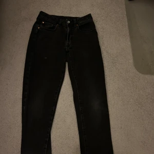 Svarta jeans med raka ben - Svarta jeans med klassisk femficksdesign och raka ben. Jeansen har hög midja och dragkedja med knapp framtill. Materialet är robust denim och färgen är något urtvättad svart för en cool look.