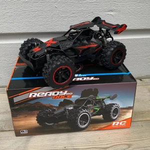 Svart och röd RC-bil Ready Race - Säljer en cool fjärrstyrd bil från Ready Race.Den är svart och röd. med robusta däck och sportig design. Bilen har detaljerade mönster och kommer med en svart fjärrkontroll. Perfekt för racing och lek utomhus.Funkar också inomhus.