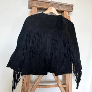 Svart mockajacka med fransar Forever 21 - Svart mockajacka från Forever 21 med långa fransar längs ryggen och ärmarna. Svart mocka.