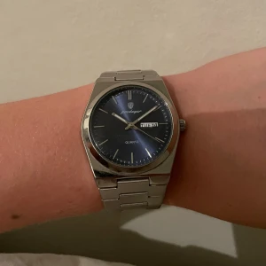 Podagar quartzklocka med blå urtavla - Hallå hallå! Säljer en tissot PRX klocka. En stilren och snygg klocka. Endast andvänd ca 30 ggr! Fick den i present men växte snabbt ut den och känner att det är dags att göra sig av med den nu efter ha legat på hyllan ett tag 😊. Tänker mig ca 1500, men kan va öppen för bud