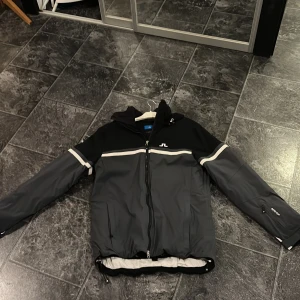 Svart och grå skidjacka J.Lindeberg L - Snygg svart och grå skidjacka från J.Lindeberg. Inköpt för ett par år sen nypris då var strax under 5000