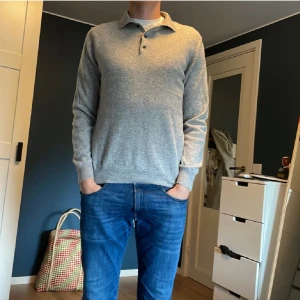 Grå pikétröja i ull/kashmir Massimo Dutti - Snygg grå pikétröja från Massimo Dutti i mjuk ull och kashmirmix. Tröjan har klassisk krage, knappar vid halsen och långa ärmar. Passformen är normal och materialet känns lyxigt och skönt mot huden. Perfekt för dig som gillar stilrena och bekväma plagg.