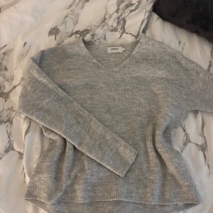 Grå ribbstickad tröja från ONLY - Mysig grå ribbstickad tröja från ONLY med v-ringning och långa ärmar. Perfekt för lager-på-lager och chill dagar. Använd max en gång 