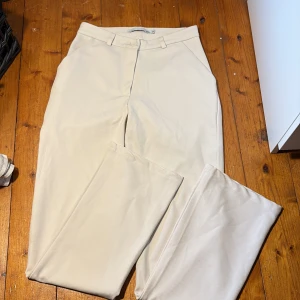 Ljus rosa kostymbyxor med raka ben - Snygga ljusrosa kostymbyxor med klassisk rak passform. Byxorna har hällor för bälte och stängs med knapp och dragkedja. Perfekta för en clean och stilren look. Materialet känns mjukt och har en lätt stretch.