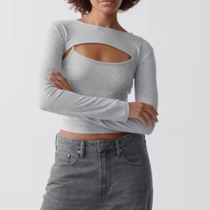 Grå croppad topp med cut-out - Säljer en ljusgrå croppad topp med lång ärm och cool cut-out detalj över bröstet. Toppen har en slim passform och är tillverkad i mjuk bomull som sitter skönt mot kroppen. Perfekt för dig som gillar trendiga och stilrena plagg.