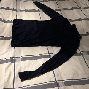 Mörkblå gymtröja  - Snygg mörkblå polotröja med lång ärm och tight passform. Tillverkad i ett mjukt och stretchigt syntetmaterial som känns skönt mot huden. Perfekt att styla med jeans eller kjol för en clean look. Används till träning detta är en vald zip i storlek s/m