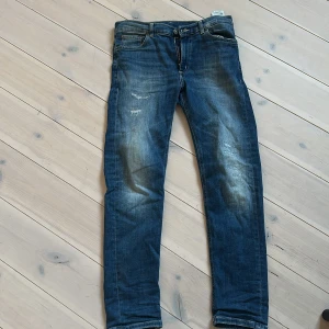 Blå jeans från Dondup med slitningar - Snygga blå jeans från Dondup med coola slitningar framtill och klassiska fem fickor. Jeansen har en rak passform och är tillverkade i mjukt bomullsdenim. Bakfickan har en broderad detalj 