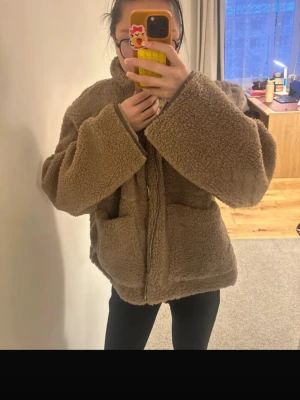 Brun oversized neo noir teddyjacka - Mysig brun teddyjacka med hög krage och stora framfickor. Jackan har en oversized passform och stängs med dragkedja. Perfekt för kalla dagar när du vill vara både varm och stylish. Skriv gärna vid intresse, behöver bli av med de akut så priset kan diskuteras!