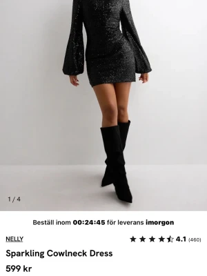 Svart glittrig kortklänning Nelly - Svart kortklänning från Nelly med glittrigt tyg, cowlneck och öppen rygg. Klänningen har långa, vida ärmar och en tight passform som framhäver figuren. Perfekt för dig som vill sticka ut med en elegant och trendig look.