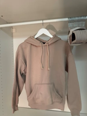 Beige hoodie med ficka framtill - Säljer en beige hoodie med huva och dragsnören. Hoodien har en stor känguruficka framtill och ribbade muddar vid ärmslut och nederkant. Perfekt för en chill och avslappnad stil. Materialet känns mjukt och bekvämt, troligen bomullsblandning. Två små fläckar som syns i bild 2, men de syns inte i helhet🤎