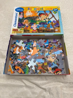 Disney Jake och piraterna pussel - Färgglatt pussel med motiv från Disney-serien Jake och piraterna från Landet Ingenstans. Pusslet har 104 bitar och kommer i en låda med illustrationer av karaktärerna. Passar barn från 3+