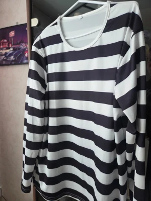 Randig långärmad tröja svart/vit - Snygg långärmad tröja med breda svarta och vita ränder. Klassisk rund halsringning och relaxed fit.Perfekt för dig som gillar en enkel men stilren look.Materialet känns mjukt och följsamt,troligen polyester.