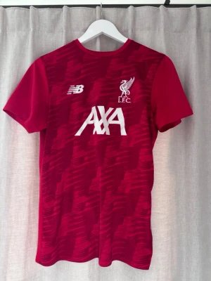 Liverpool New Balance stl: S - Röd kortärmad träningströja från Liverpool FC från new balance. Storlek S, knappt använd.