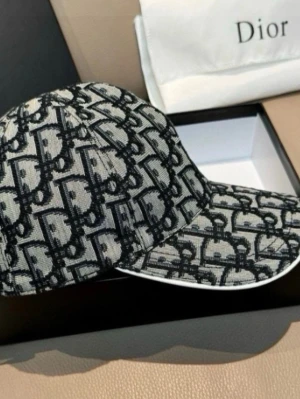 Christian Dior monogram keps - Snygg keps från Christian Dior med ikoniskt svart och grått monogrammönster över hela kepsen. Märkets logga är broderad på sidan. Kepsen har böjd skärm och vit kantdetalj. Tillverkad i textilmaterial som känns exklusivt och trendigt.