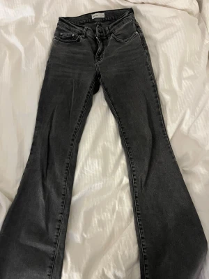 Svarta bootcut jeans från Gina Tricot - Säljer ett par svarta mid Rise bootcut jeans från Gina Tricot med klassisk femficksmodell. Jeansen har en snygg tvättad look och utsvängda ben som ger en trendig siluett. Perfekta för dig som gillar en avslappnad sopranostil.