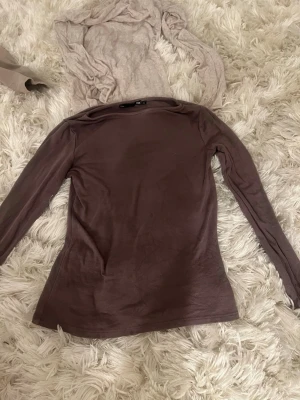 Brun långärmad topp från 157 - Säljer en enkel och stilren brun långärmad topp från 157 i storlek XS. Toppen har en rund halsringning och är gjord i mjukt bomullsmaterial som känns skönt mot huden. Perfekt att matcha med jeans eller kjol för en clean look.