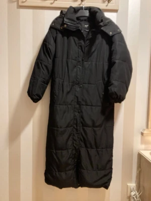 Svart lång vinterjacka - Lång svart vinterjacka med luva. 