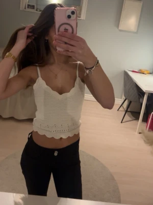 Vit virkad croppad linnetopp - Säljer en söt vit virkad linnetopp med smala axelband och vågig kant nertill. Top sopassad och croppad modell, perfekt för varma dagar. Supersnygg till både jeans och kjol!