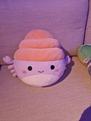 Squishmallows krabba - Supermjuk och gullig Squishmallows kudde formad som en sushibit med lax. Kudden är ljusrosa, orange och vit med sött ansikte och små rosa kinder. Perfekt som prydnad eller mysig kudde i soffan eller sängen. Kostar 290 kr ny