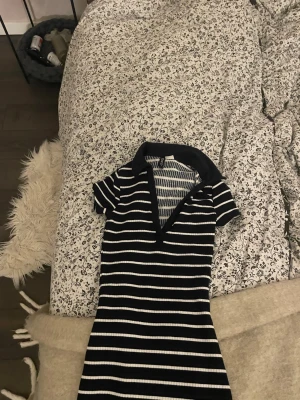 Marinblå randig kortklänning med krage - Snygg kortklänning i marinblått med vita horisontella ränder och djup v-ringning. Klänningen har korta ärmar och en klassisk krage som ger en sportig vibe. Perfekt för dig som gillar en avslappnad men trendig stil.