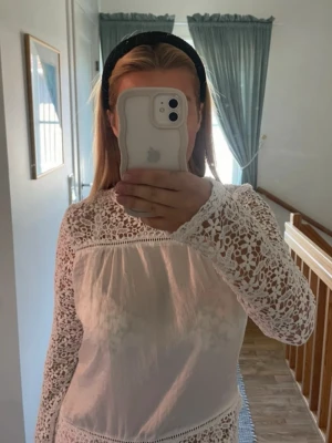 Vit spetsblus med lång ärm - Säljer en superfin vit blus med genombruten spets upptill och på ärmarna. Blusen har rund halsringning och är tillverkad i ett tunt, lätt material. Från NLY trend i storlek 36