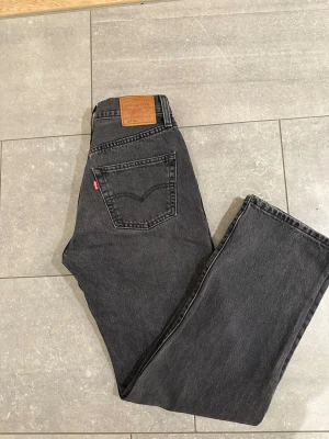 Levi's 501 grå jeans  - Säljer ett par klassiska Levi's 501 jeans i snygg mörkgrå. Rak passform  och ikonisk läderpatch bak. Jeansen har fem fickor och är tillverkade i robust bomullsdenim. Perfekta för en avslappnad och tidlös look. Längd=32 och midja=26