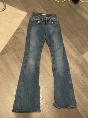 Blå bootcut jeans från Ginatricot - Klassiska blå jeans från Gina  med bootcut-passform. Jeansen har fem fickor, normal midja och är tillverkade i slitstarkt denim. Perfekta för dig som gillar en tidlös och avslappnad stil. Doch har de ganska mycket slitage.