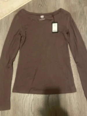 Brun långärmad topp från H&M - En basic brun långärmad topp från H&M med rund halsringning. Perfekt att styla med jeans eller kjol för en enkel och clean look. Tillverkad i mjuk bomull som känns skön mot huden.