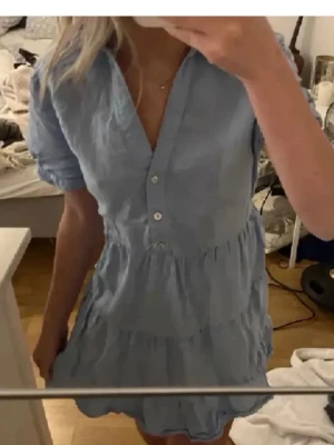 Ljusblå kort klänning med volanger - Supersöt ljusblå kortklänning med volanger och v-ringning. Klänningen har korta ärmar, knappar framtill. Från Zara❤️