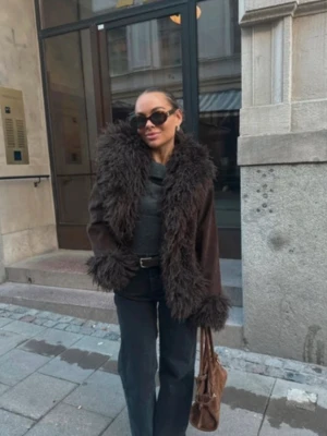 Brun pälsjacka från NA-KD - Snygg brun pälsjacka från NA-KD med fluffig fuskpäls runt krage, ärmslut och nederkant. Jackan har en loose passform och är perfekt för att ge din outfit en trendig touch. Tillverkad i syntetmaterial och pälsimitation.